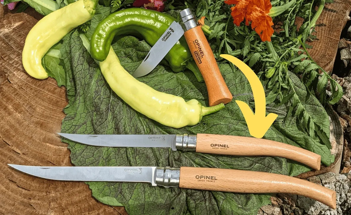 Opinel knives with wooden handles on a wooden surface with green leaves and flowers.