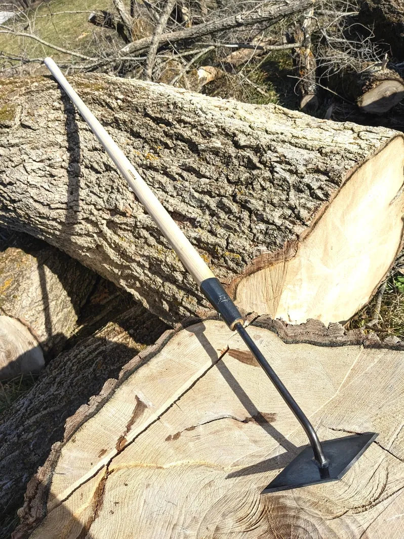 Scuffle Weeder, Hand Forged Garden Tool, Long Handle on tree log.